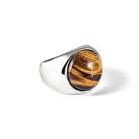 A silver ring with a wide polished band featuring a large oval cabochon of golden-brown tiger's eye stone set in a bezel.