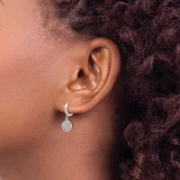 A person wearing a silver crescent-shaped hoop earring with a small circular pendant hanging from it, shown from the side against their ear and dark curly hair.