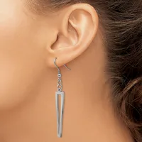 A silver-toned dangle earring with an elongated rectangular tube pendant hangs from a hook-style ear wire on a model's ear.