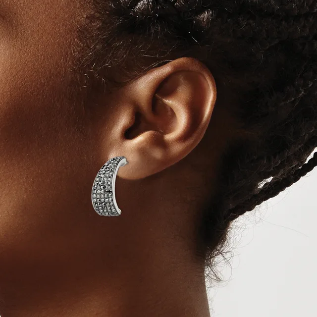 A curved silver-toned crescent earring densely covered with small round crystals or rhinestones, worn on a person's earlobe.