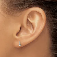 Close-up side view of a person's ear wearing a small silver stud earring with a minimalist cylindrical design.