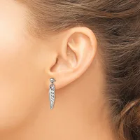 A woman wearing a silver twisted teardrop-shaped dangle earring with a post and ball closure, shown from the side view of her ear.