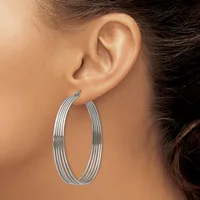 A woman wearing large oval silver hoop earrings with multiple parallel ridged bands, shown from the side profile view of her head and ear.