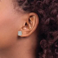A close-up side view of a person wearing a square-shaped stud earring with a gridded pattern and small stones set in a white metal, against their ear.