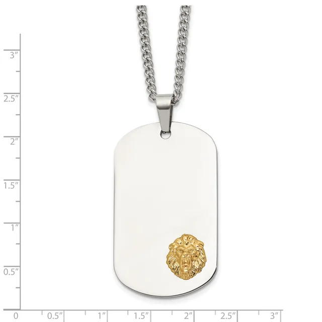 Stainless steel dog tag pendant with a gold-toned lion head emblem, suspended from a curb chain, shown against a measurement scale.