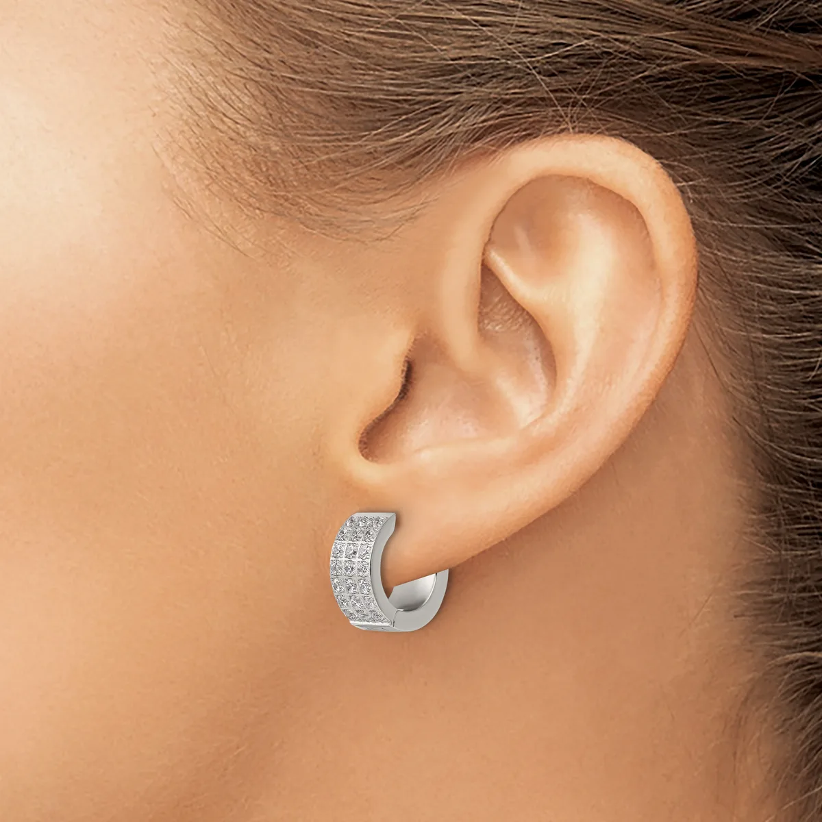 A silver chunky hoop earring with a textured surface set with small cubic zirconia stones, worn on a person's ear.