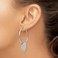 A woman wearing a pair of silver hoop earrings with tassel fringe details hanging from the bottom, shown from the side view of her ear and neck.