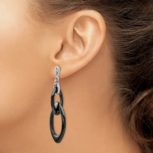 A woman wearing a pair of dangling chain link earrings in black and silver metal, shown from the side view of her ear and neck.