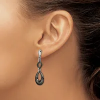 A woman wearing a dangling earring with a chain link design and teardrop-shaped pendant in silver and dark metal tones.