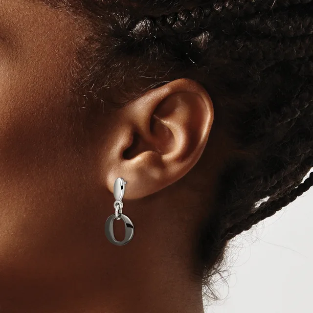 A person wearing a silver drop earring with a hinged hoop design, shown from the side view against their ear and neck.