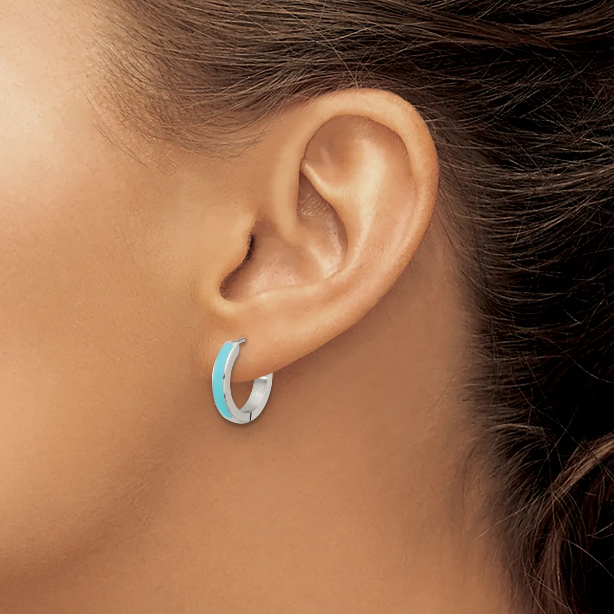 A person wearing a light blue curved hoop earring in their earlobe, shown from a side profile view.