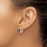 A small curved hoop earring with a two-tone finish of silver and black enamel worn on the earlobe of a person shown from the side.