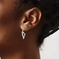 A person wearing a diamond-shaped silver drop earring with a twisted or chevron pattern, shown from the side view against their ear.