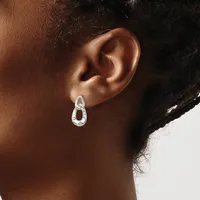 A person wearing a silver teardrop-shaped earring with a small stamped hallmark, shown from the side profile of their ear and neck.