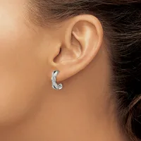 A person wearing a curved silver hoop earring with a textured surface in their pierced earlobe.