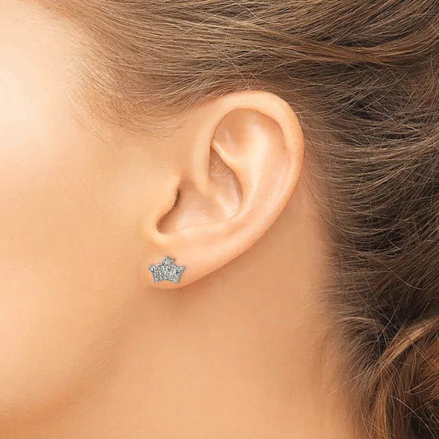 A small star-shaped stud earring set with diamonds or crystals is worn in a woman's earlobe.