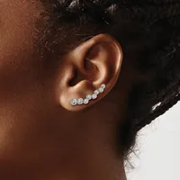A person wearing a curved ear crawler earring with multiple round diamond studs set in white metal along the upper ear.