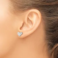 A person wearing a small silver heart-shaped stud earring with a small diamond or gemstone accent, shown on their earlobe from a side profile view.