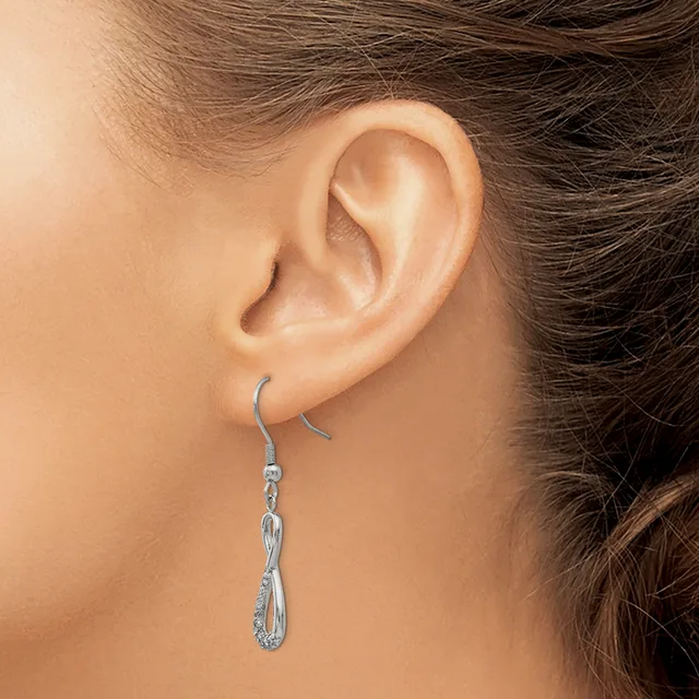 A silver teardrop-shaped dangle earring hangs from a curved hook on a person's earlobe.