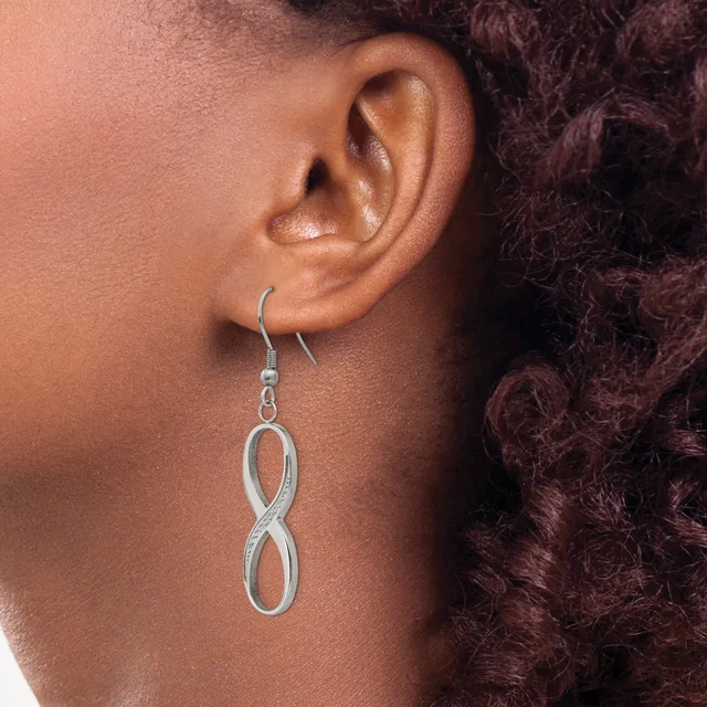A person wearing a silver infinity symbol dangle earring on a fish hook backing, shown from the side profile against their ear.