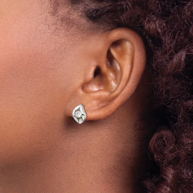 A close-up view of a person's ear wearing a teardrop-shaped silver earring with a small round diamond or crystal stone in the center.