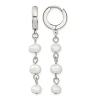 A pair of silver huggie hoop earrings with three white pearl beads dangling from each hoop on chain links.
