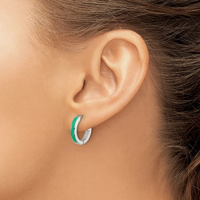 A person wearing a green and silver curved hoop earring in their earlobe, shown in profile view.