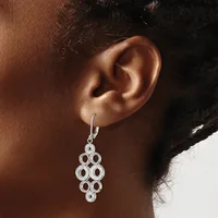 A silver chandelier-style earring with circular open links arranged in a tiered diamond pattern hangs from a leverback hook on a model's ear.