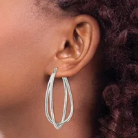 A person wearing silver-toned double-loop hoop earrings with a textured finish, shown in profile against their ear and neck.