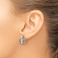 A silver-toned circular earring with a vertical bar detail worn on a person's earlobe.