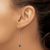 A person wearing a long silver threader earring with a small dark stone pendant, shown from the side view of their ear and neck.