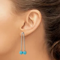 A person wearing long dangling earrings with turquoise blue spherical stones suspended from thin silver chain threaded through pierced earlobes.