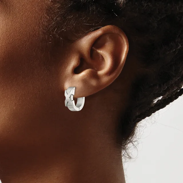 A person wearing a small silver chunky curved hoop earring in their earlobe, shown in profile against a neutral background.