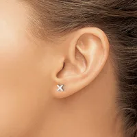 A person wearing a small silver X-shaped stud earring in their earlobe, shown from the side profile of their head and neck.