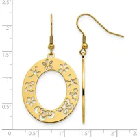 Gold-tone dangle earrings with oval frames decorated with cutout floral patterns, displayed on a measurement scale.