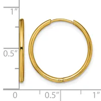 A pair of gold-toned hoop earrings with a polished finish displayed against a ruler showing measurements up to one inch.