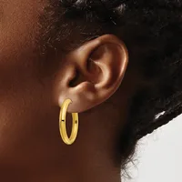A person wearing a pair of polished gold hoop earrings, shown from the side view of their ear and neck.