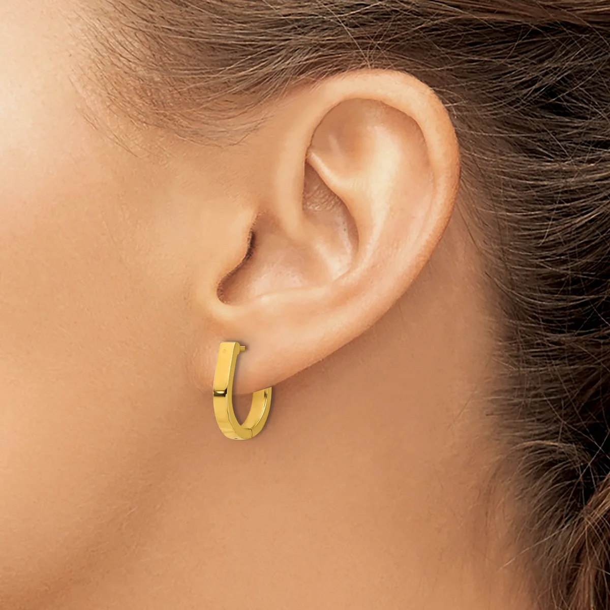 A woman wearing a small gold hoop earring in her earlobe, shown in profile against her neck and shoulder.