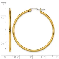 A pair of polished gold hoop earrings with hook closures, displayed against a ruler showing they measure approximately 1.5 inches in diameter.