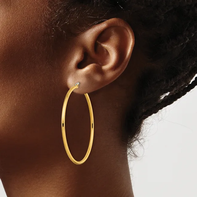 A person wearing a large gold oval hoop earring visible from the side profile, with the ear lobe pierced at the center.
