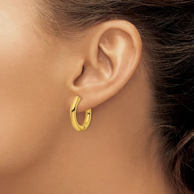 A person wearing a pair of polished gold hoop earrings, shown from the side profile of their ear and neck.