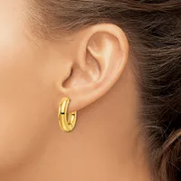 A person wearing a pair of polished gold hoop earrings with a chunky, rounded profile, shown from the side view of their ear and neck.