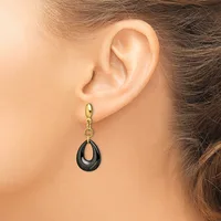 A woman wearing a gold hoop earring with a dangling black teardrop pendant shown from the side view of her ear and neck.