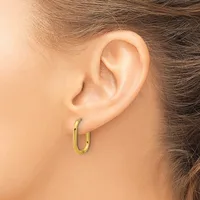 A person wearing small gold-colored oval hoop earrings, shown from the side profile displaying the ear and nearby hair.