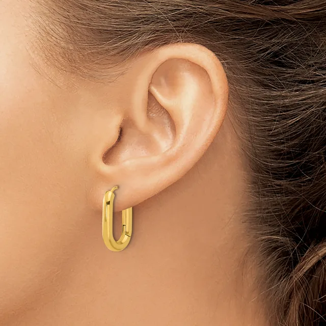 A person wearing a small gold-colored oval hoop earring in their earlobe, shown in profile view.