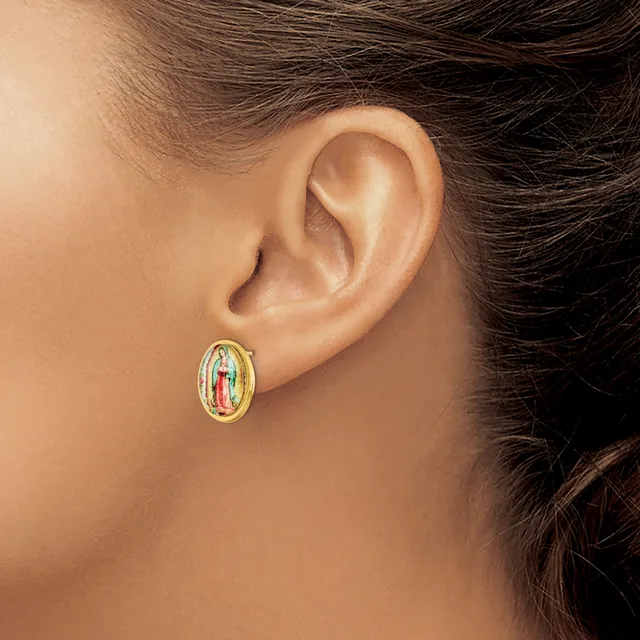 A person wearing a small oval gold earring with a white enamel center featuring a colorful religious image, shown from the side view near the ear.