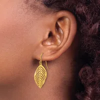 A person wearing a gold leaf-shaped drop earring with detailed vein texturing, shown from the side profile against their neck and shoulder.