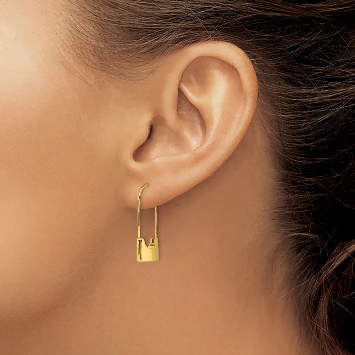 A person wearing gold-toned rectangular padlock earrings with curved wire hooks, shown from the side view of their ear and neck.
