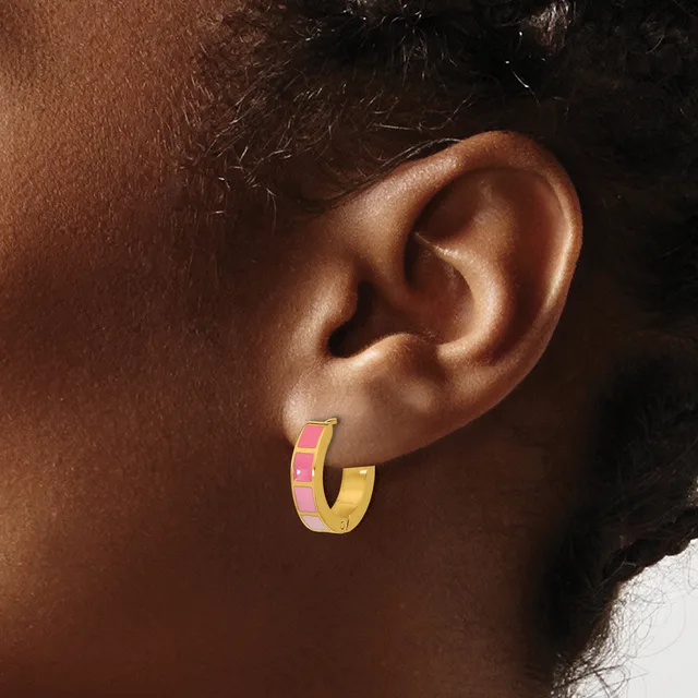 A person wearing a gold hoop earring with a pink enamel stripe on the upper portion, shown from the side profile against their ear.