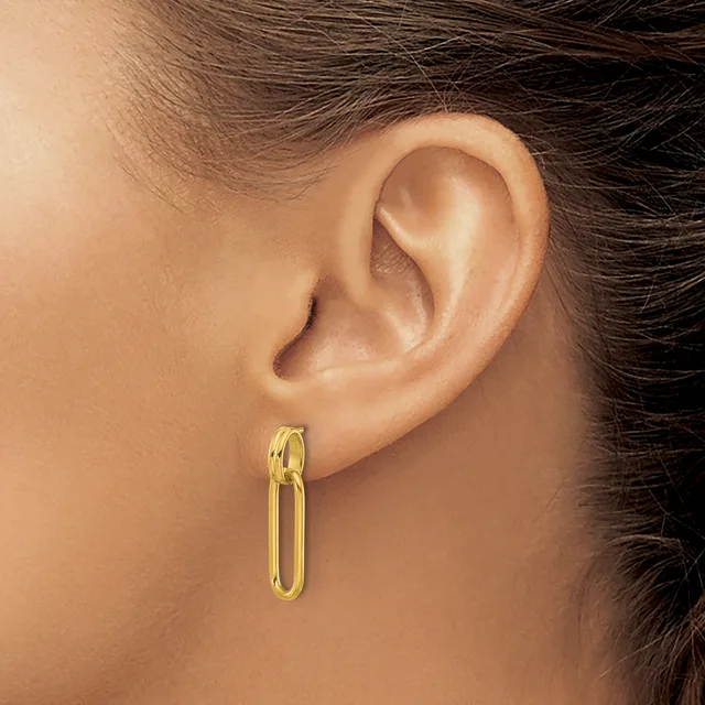 A woman wearing a gold oval hoop earring in her earlobe, shown in profile view.